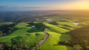 Sunset aerial view of Mount Alma Road winding through green hills and valleys near Adelaide, South Australia