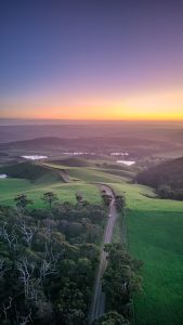 Sunset aerial view of Mount Alma Road winding through green hills and valleys near Adelaide, South Australia