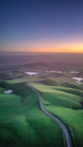 Sunset aerial view of Mount Alma Road winding through green hills and valleys near Adelaide, South Australia