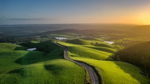 Sunset aerial view of Mount Alma Road winding through green hills and valleys near Adelaide, South Australia