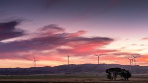 Wind turbines along Worlds End Highway at sunset, captured in warm evening light as the outback sky glows in orange and gold – landscape photography by Junrui Ye