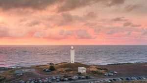 Cape Jervis Lighthouse glowing under the warm hues of sunset, overlooking the rugged coastline of South Australia – landscape photography by Junrui Ye