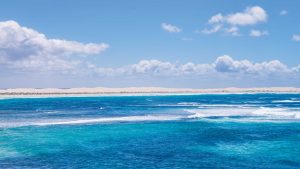 Turquoise Waters of Fowlers Bay – Minimal Seascape Photography South Australia Turquoise ocean waves at Fowlers Bay South Australia with sandy dunes in the background under a clear blue sky minimal seascape composition