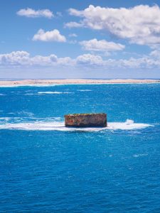 Lone Rock Formation in Fowlers Bay – Dramatic Ocean Landscape South Australia Isolated rock formation in the ocean at Fowlers Bay South Australia surrounded by deep blue water and gentle waves under a bright sky