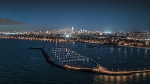 Melbourne Skyline at Blue Hour – St Kilda Pier Aerial Night Photography Aerial view of Melbourne skyline at blue hour from St Kilda Pier with marina boats illuminated and city lights reflecting on the bay