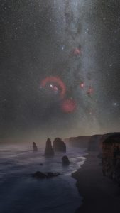 Milky Way with red emission nebulae above the Twelve Apostles in Victoria Australia with ocean coastline at night