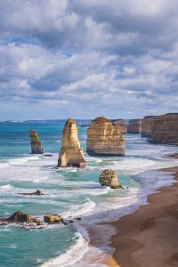 Sunlit limestone stacks at the Twelve Apostles with turquoise water and sandy coastline
