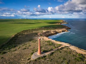 Troubridge Point Lighthouse and Yorke Peninsula Coastline Drone view of Troubridge Point Lighthouse overlooking the rugged Yorke Peninsula coastline, with farmland and distant wind turbines in South Australia.