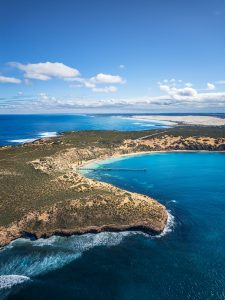 Aerial view of Point Sinclair coastline and jetty surrounded by turquoise waters and coastal dunes in South Australia