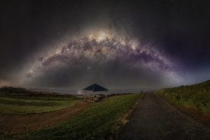A panoramic Milky Way arch stretching across the night sky above Haycock Point Lookout and the Carrickalinga coastline in South Australia.